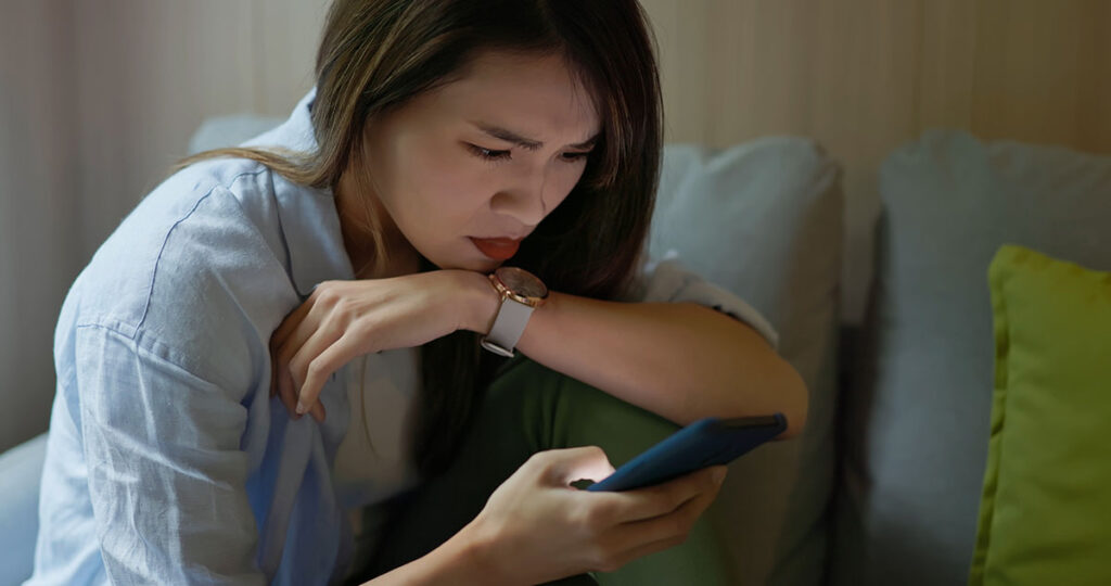 Woman looking at phone with worried expression
